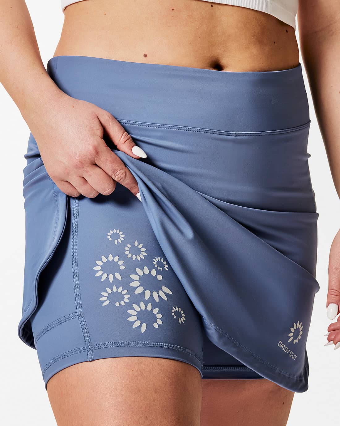 Sportkjol med blomtryck i reflex på innerbyxan. Dimblå färg. Rak modell med slitsar i sidorna.